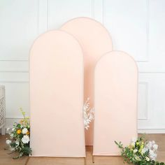 three pink arches with white flowers on the floor in front of them and one is open