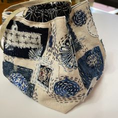 a handbag is sitting on a table with white and blue material in the background