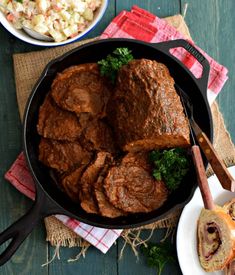 some meat and vegetables in a pan on a wooden table next to other food items