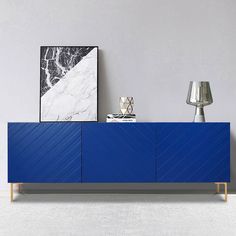 a blue sideboard sitting next to a lamp on top of a white carpeted floor