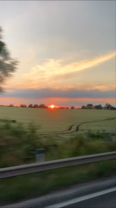 the sun is setting over an open field