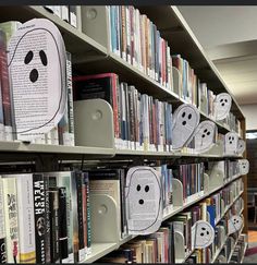 some books are lined up on shelves in a library with ghost faces drawn on them