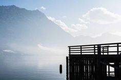 a person sitting on a bench next to a body of water with mountains in the background