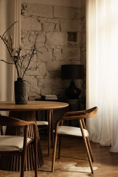 a table with two chairs and a vase on top of it next to a window