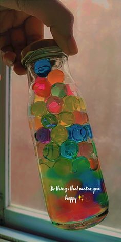 a hand is holding a jar filled with colorful buttons and the words do things that make you happy