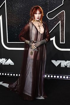 a woman with red hair wearing a long dress and gloves on the black carpet at an event