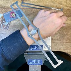 a person with a watch on their wrist holding onto a piece of metal that is attached to a table