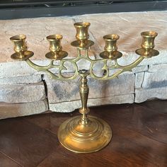 a brass candelabra with five candles on it in front of a brick fireplace