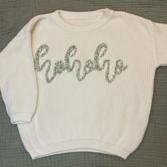 a white sweater with green lettering on the front and bottom that says goshelop