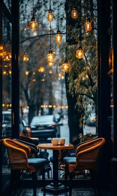 two chairs and a table in front of a window with lights hanging from the ceiling