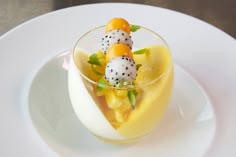 there is a small dessert in the glass on the plate with fruit and garnishes