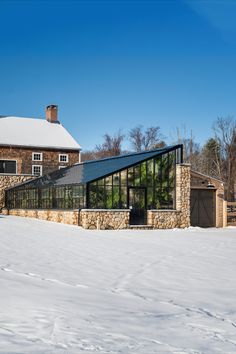 the house is surrounded by snow and has a large glass wall on it's side