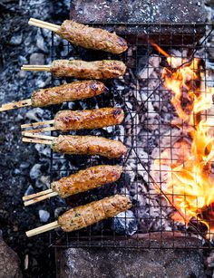 several skewered meats are being cooked on the grill over an open flame