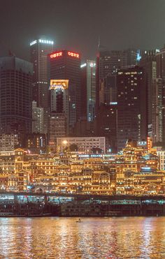 the city skyline is lit up at night, with lights reflecting off the water and buildings in the background