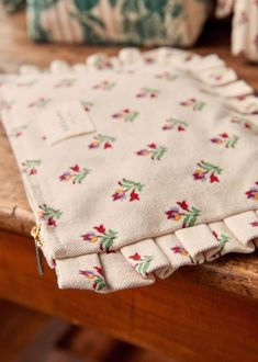 an old cloth with flowers on it sitting on a wooden table next to other items