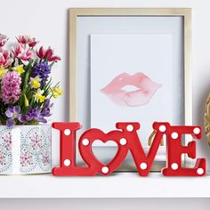 the word love spelled with polka dots sits on a shelf next to flowers