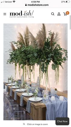 the table is set with place settings and flowers in vases on each side, along with greenery