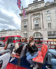 two women sitting on seats in front of a building with an union jack flag hanging from the roof