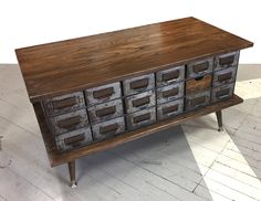 an old wooden cabinet with many drawers on the top and bottom, sitting on a white floor