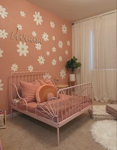 a pink and white bedroom with flowers painted on the wall, bedding and pillows