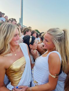 two beautiful women standing next to each other in front of a crowd