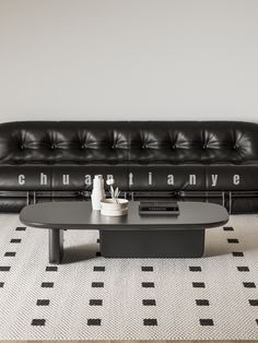 a black leather couch sitting next to a coffee table on top of a white rug