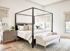 a bedroom with a four poster bed and white walls