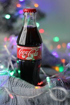 a coca - cola bottle sitting on top of a blanket next to a christmas tree