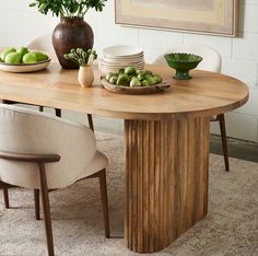 a wooden table topped with plates and bowls filled with green fruit sitting on top of a rug