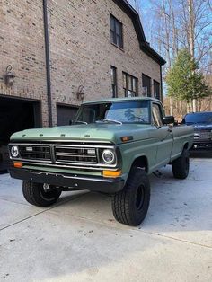 a green truck parked in front of a brick building