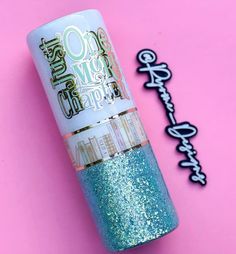 a tube of glitter sitting on top of a pink surface