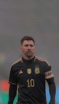 a man standing in front of a soccer ball wearing a black shirt and yellow shorts