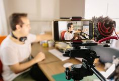 a man sitting in front of a desk with a camera and headphones on it