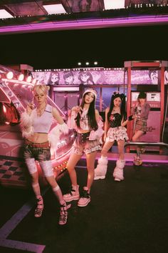 girls standing in front of a bus with lights on it's sides and wings