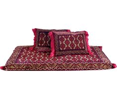 three pillows on top of each other with red and gold designs in the middle,