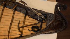 an old wooden boat is on display with other items around it and some sticks sticking out of the side