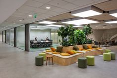 an office with couches, tables and plants in the middle of the floor area