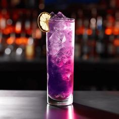 a purple drink with ice and lemon wedges on the rim, sitting on a bar