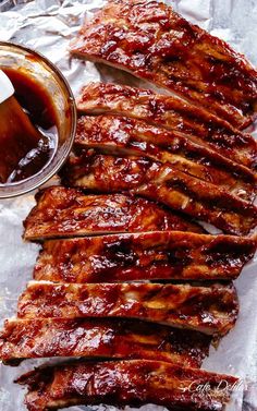 barbecue ribs on foil with bbq sauce and ketchup next to it, ready to be eaten