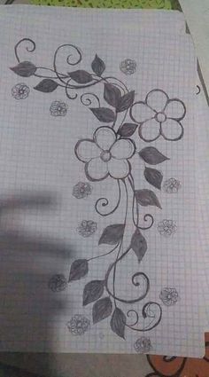 a piece of paper with flowers and leaves drawn on it, sitting on top of a table