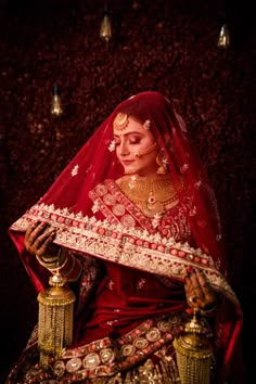 a woman dressed in red and gold is holding a golden lamp with her hand on it