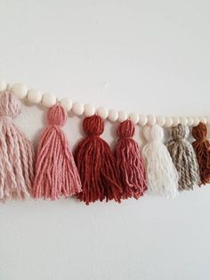 the tassels are hanging on the wall in different colors and sizes, along with white beads