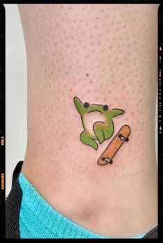 a person with a skateboard on their foot and a frog tattoo on the leg