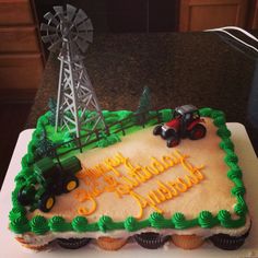 a birthday cake with tractor and farm scene on it, sitting on a counter top