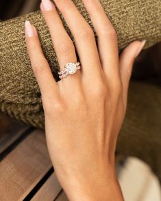 a woman's hand with a diamond ring on her left hand, sitting on a wooden bench