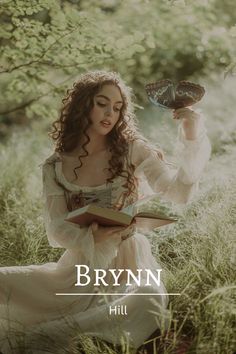 a woman sitting in the grass holding a book