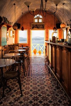 the inside of a restaurant with lots of tables and chairs in front of an open door