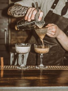 a bartender pours an alcoholic drink into three glasses