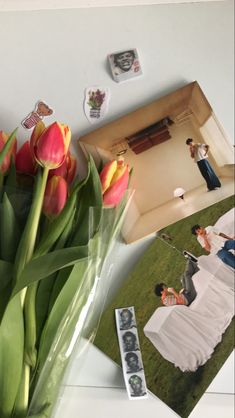 a bouquet of tulips sitting on top of a white table next to pictures