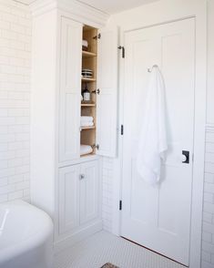 a bathroom with white walls and flooring next to a bathtub filled with towels